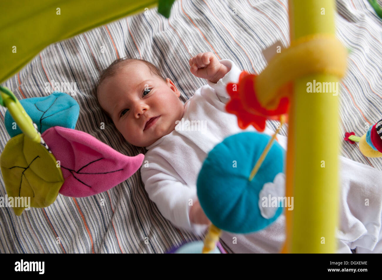 Little baby girl lying under a play gym Stock Photo