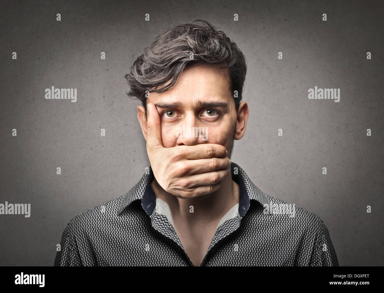 Man with a hand that keeps his mouth shut Stock Photo