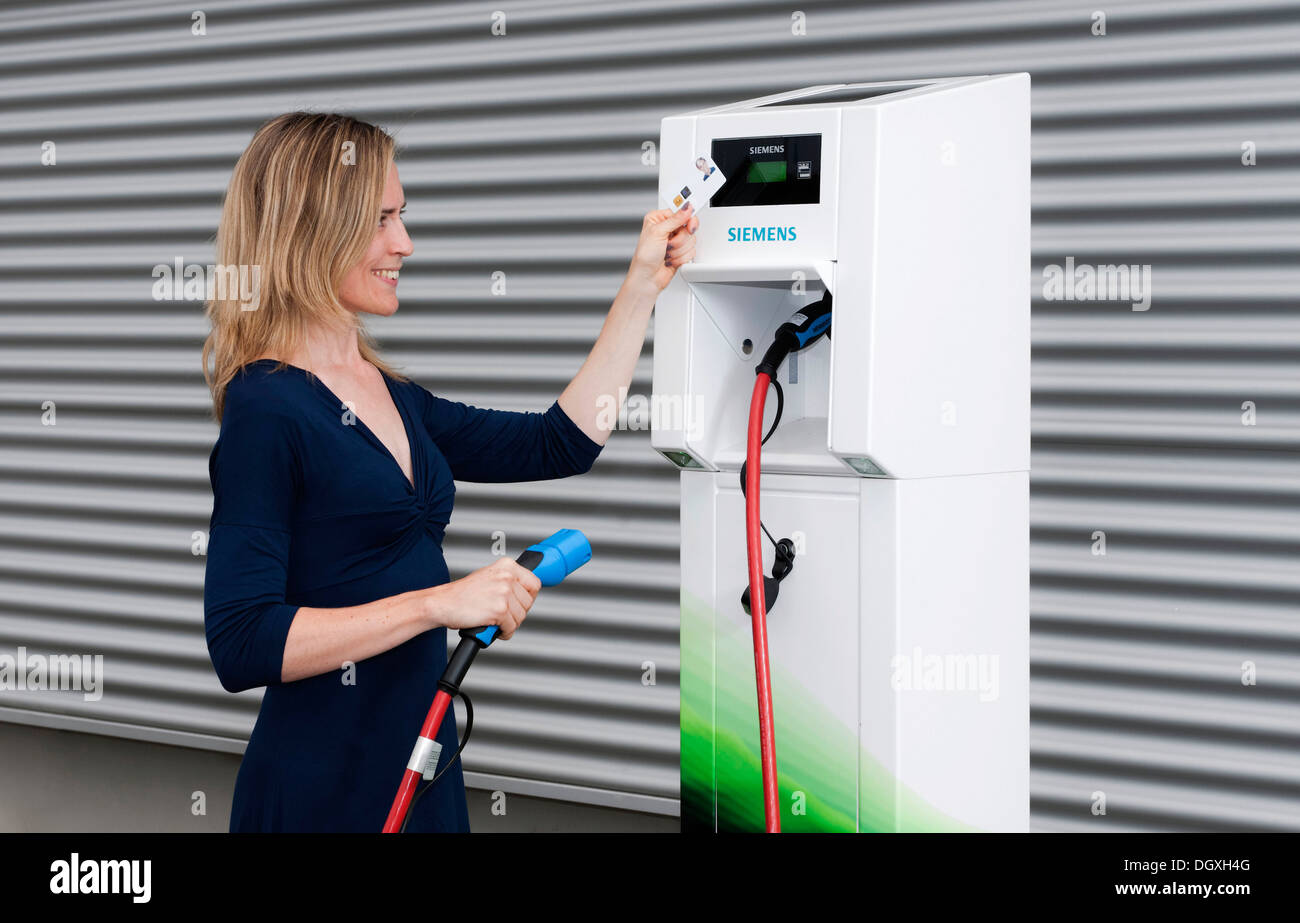 Woman holding a code card in front of the reader of a Charge CP700A charging station by Siemens, Fuerth, Bavaria Stock Photo