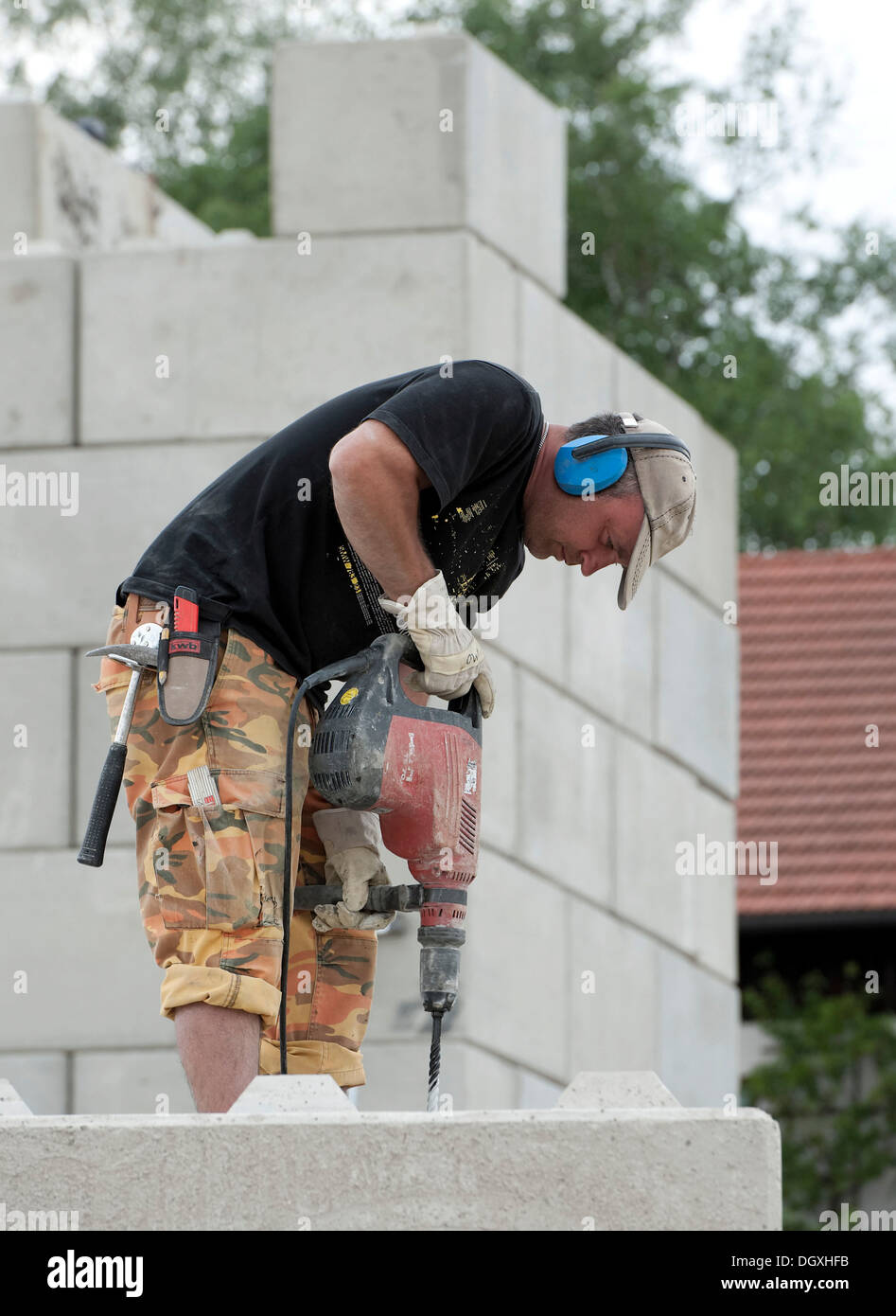 Construction worker drilling holes into concrete blocks during a