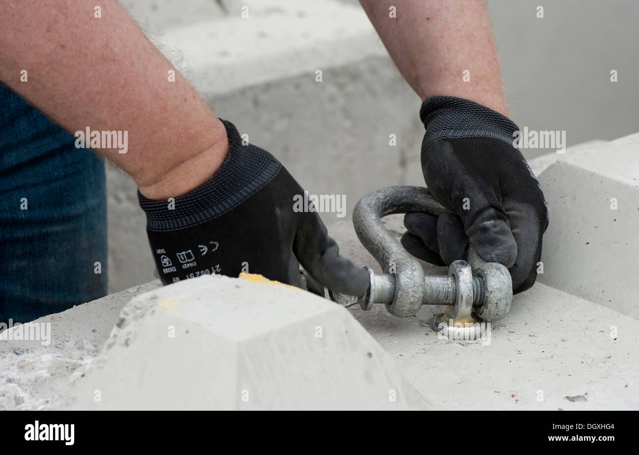 Construction worker screwing a shackle into a concrete block that is