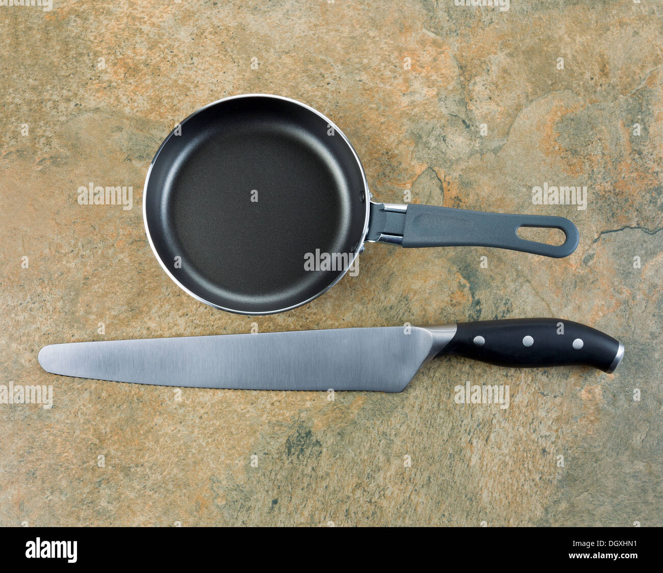 Photo of large serrated knife and frying pan on natural stone counter