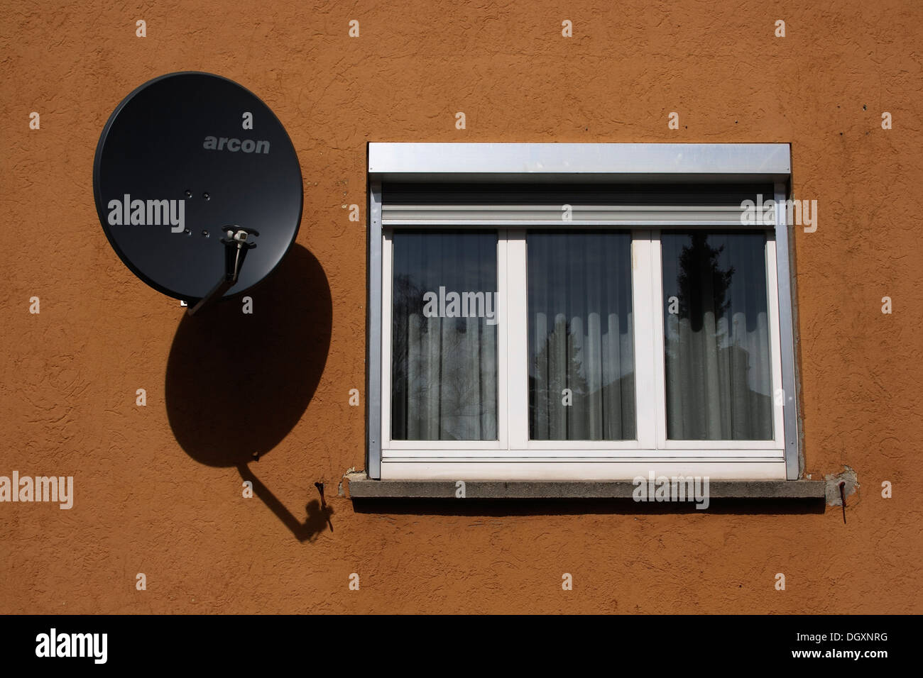 Satellite dish next to a window on a house wall Stock Photo