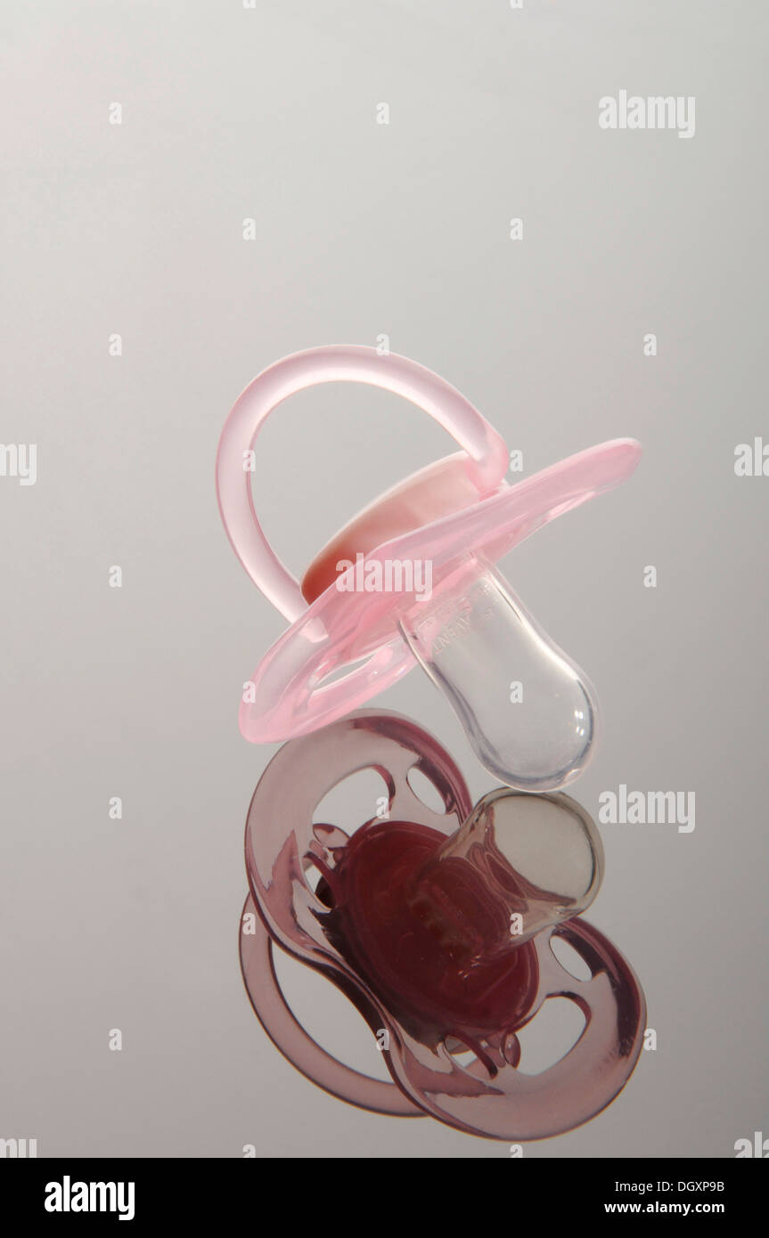 Pink pacifier on a reflective surface Stock Photo