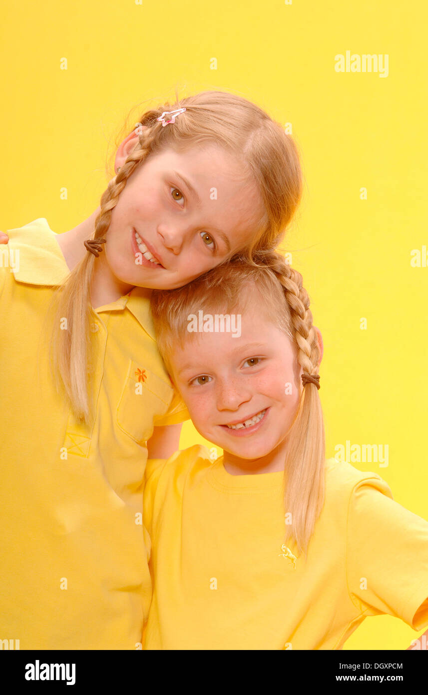 Boy and girl, brother and sister, standing arm in arm, smiling Stock Photo