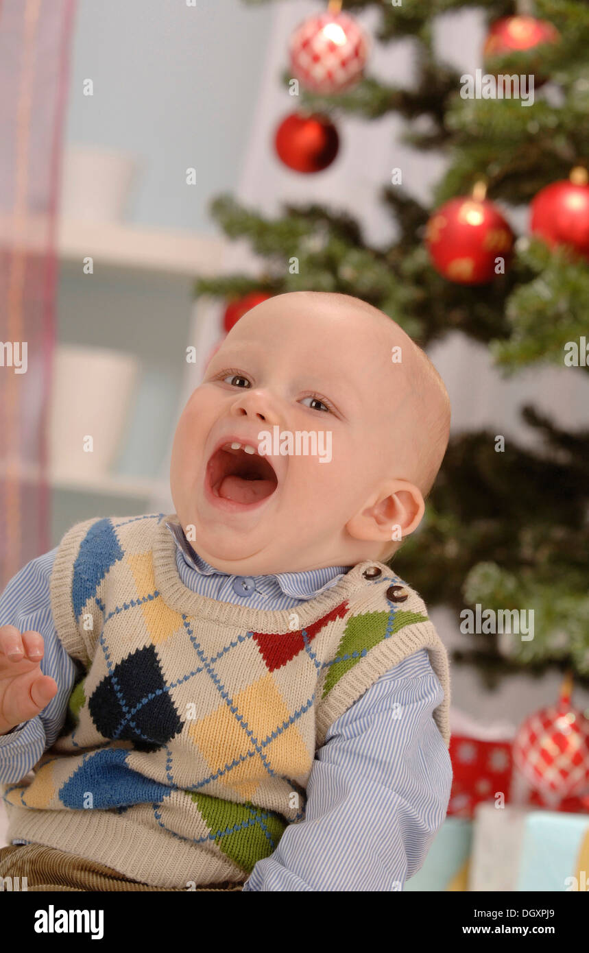 Toddler singing in front of a Christmas tree Stock Photo