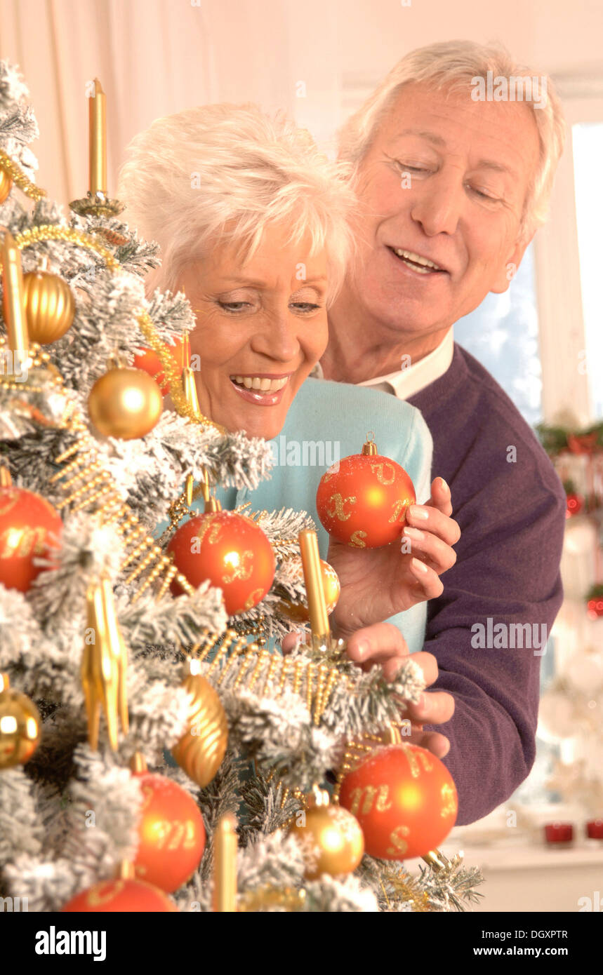 Mature couple smiling while decorating a Christmas tree Stock Photo