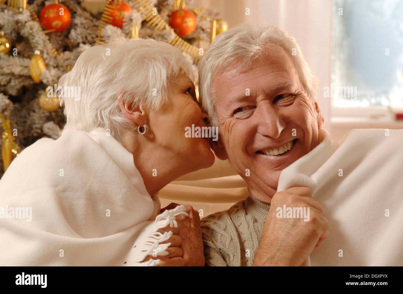 Mature couple in love wrapped in a blanket sitting in front of a Christmas  tree Stock Photo - Alamy