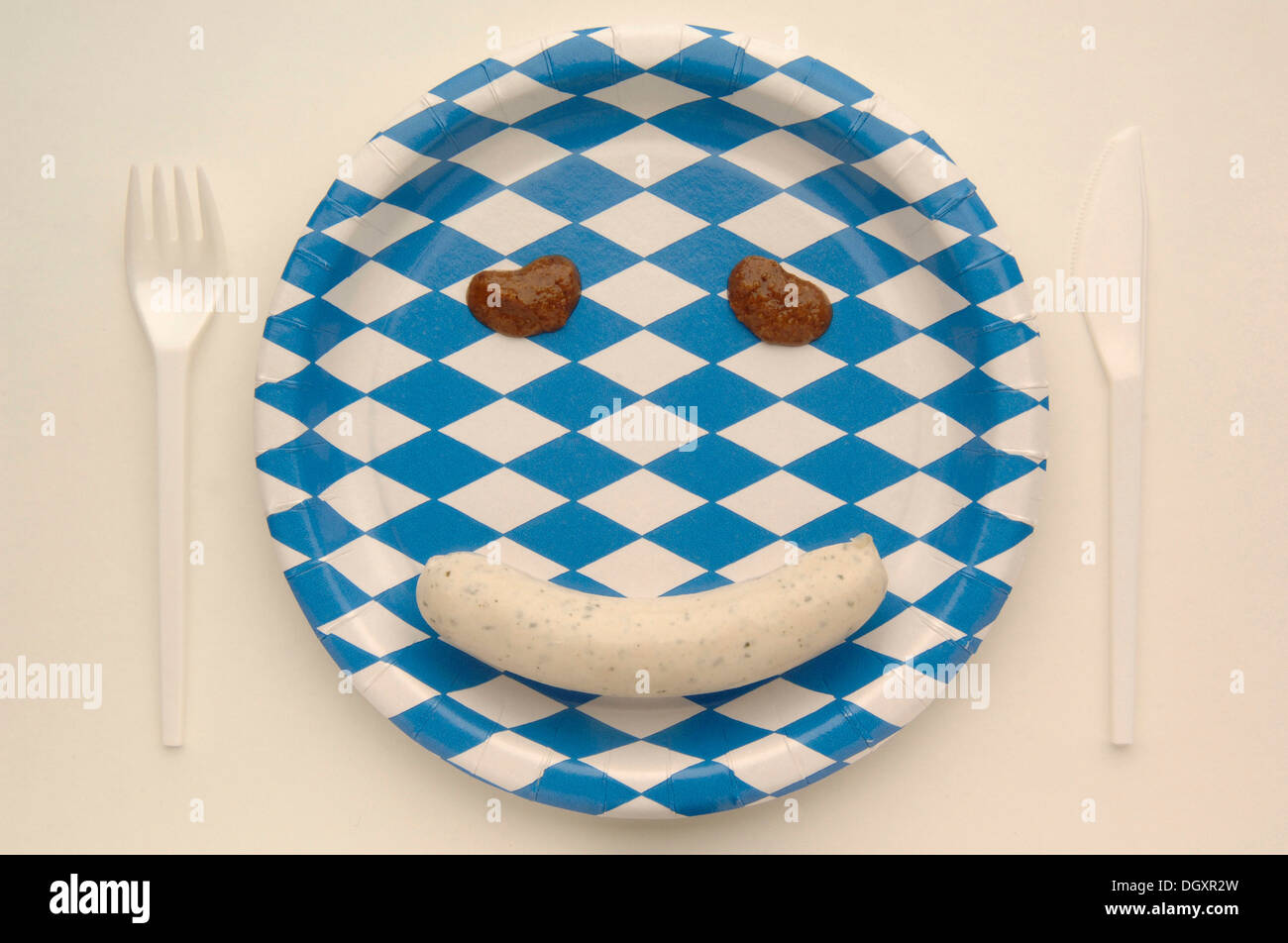 Weisswurst veal sausage making a face with mustard on a paper plate with the Bavarian diamond pattern Stock Photo