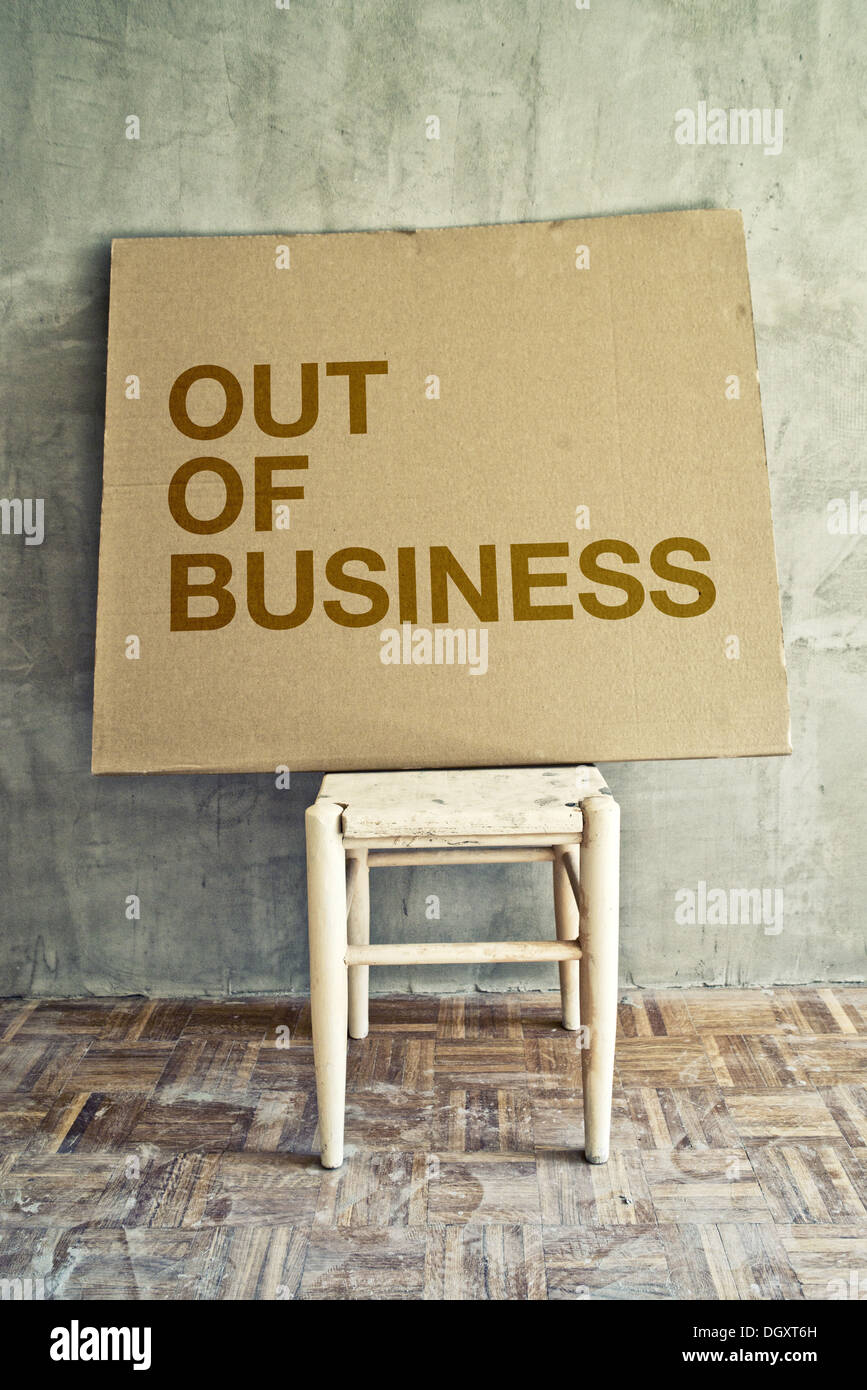 Out of business message on cardboard left on empty chair in obsolete room. Stock Photo
