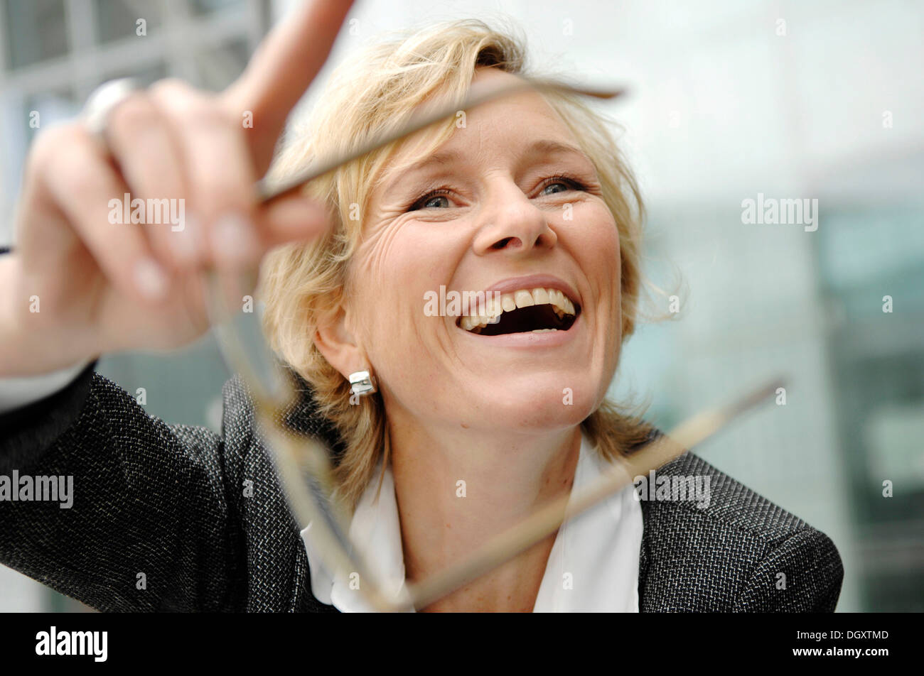 Smiling business woman, 40-50, holding her glasses Stock Photo