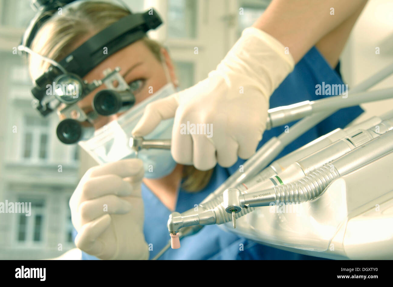 Dentist wearing magnifying loupes preparing a drill Stock Photo