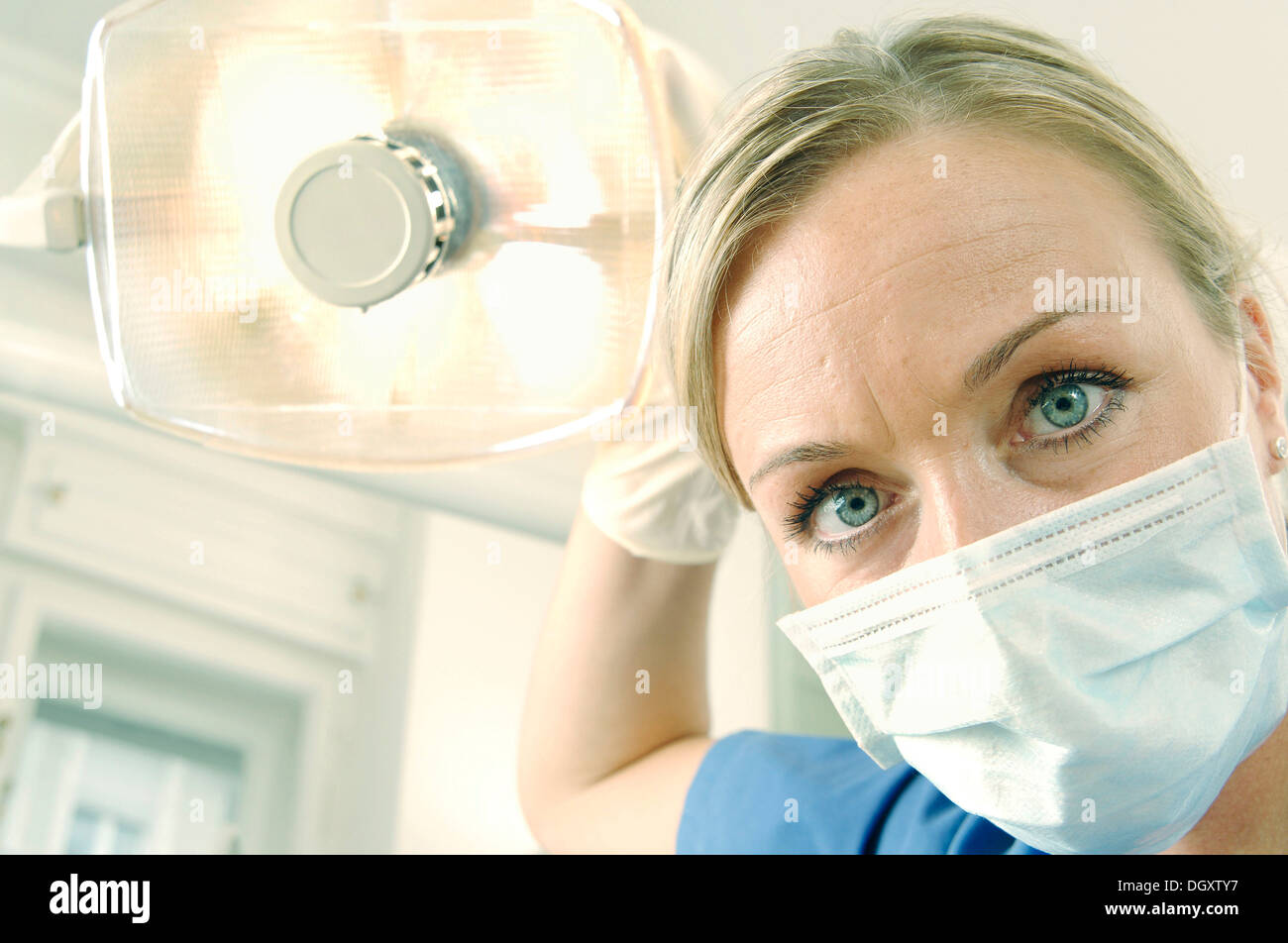 Dentist, dental hygienist, wearing a face mask and adjusting a dentist