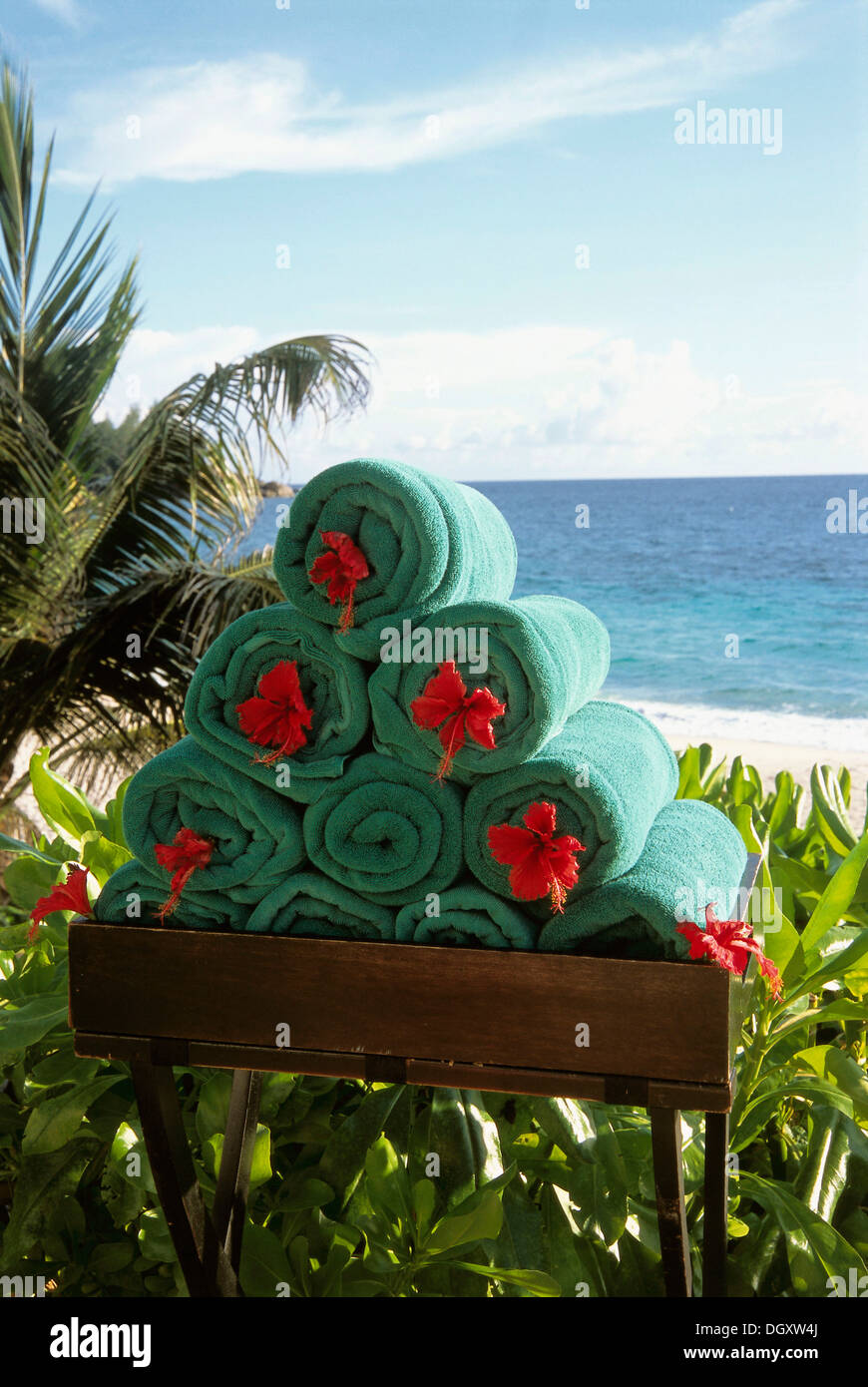 Stack of rolled towels with red flower on the beach, Mahe, Seychelles Stock Photo