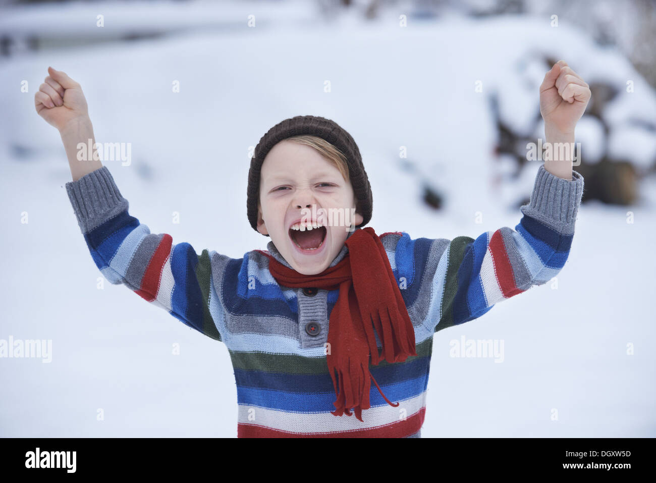 Boy in a winter sweater and a scarf, shouting with fists raised Stock Photo