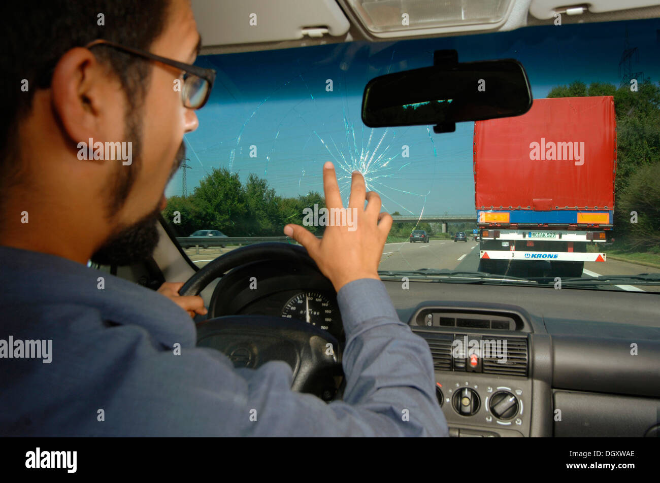 Shocked motorist reacting after a rock has hit the windscreen of his car Stock Photo