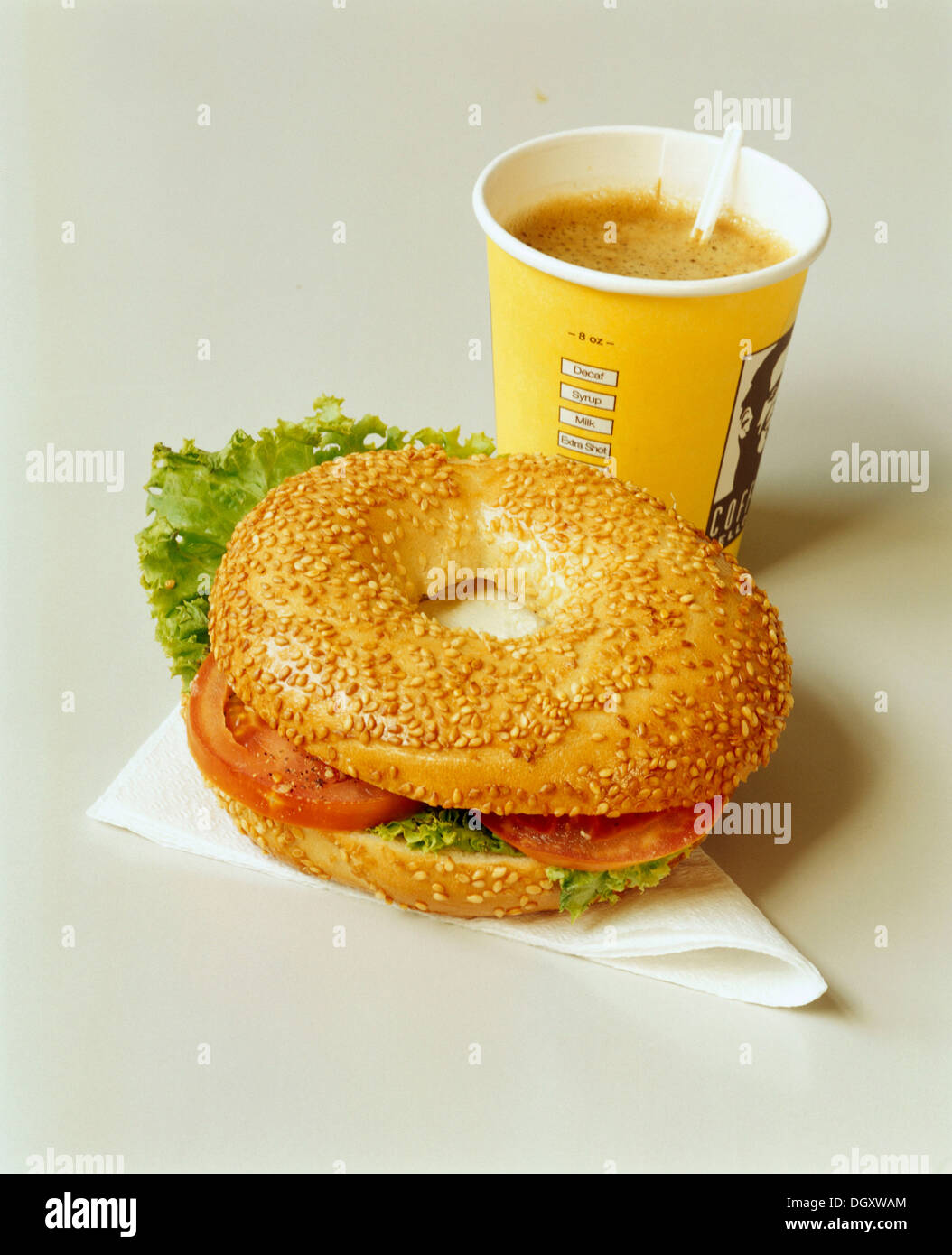 Filled bagel on a serviette and coffee in a paper cup Stock Photo