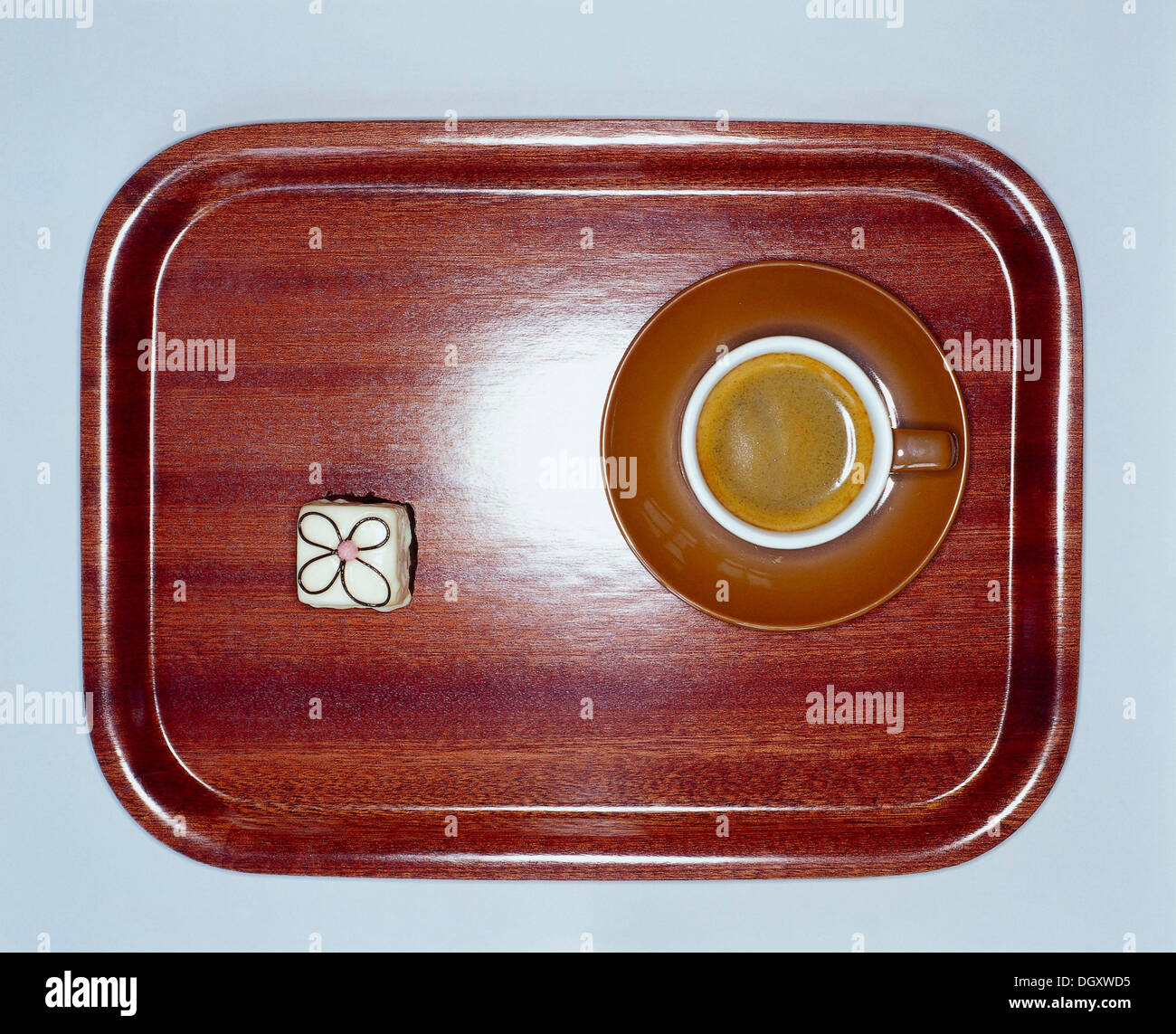 Small wooden tray with coffee and a petit four from above Stock Photo