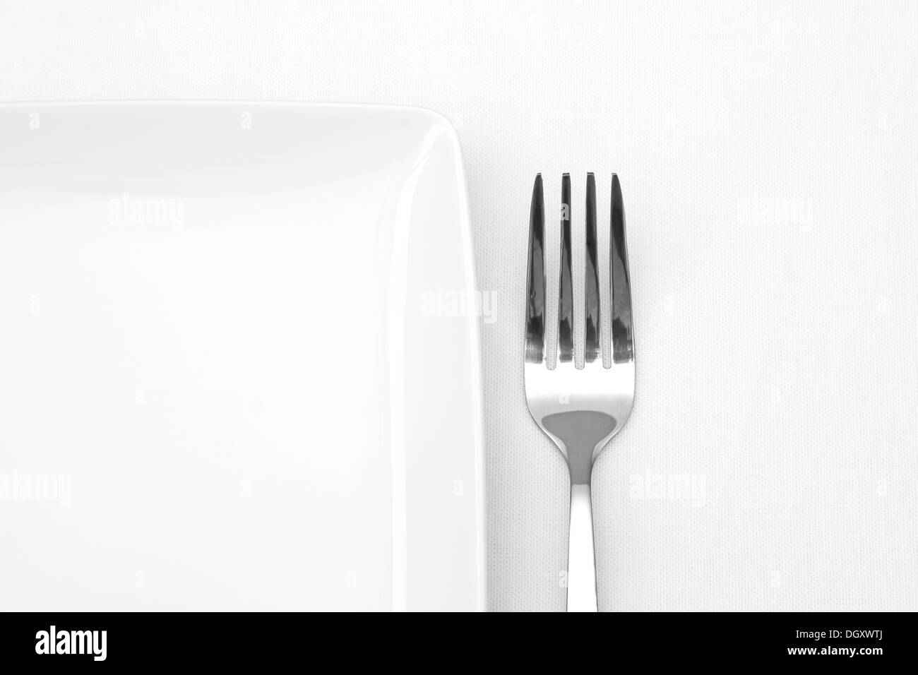 White plate with fork on white table cloth Stock Photo