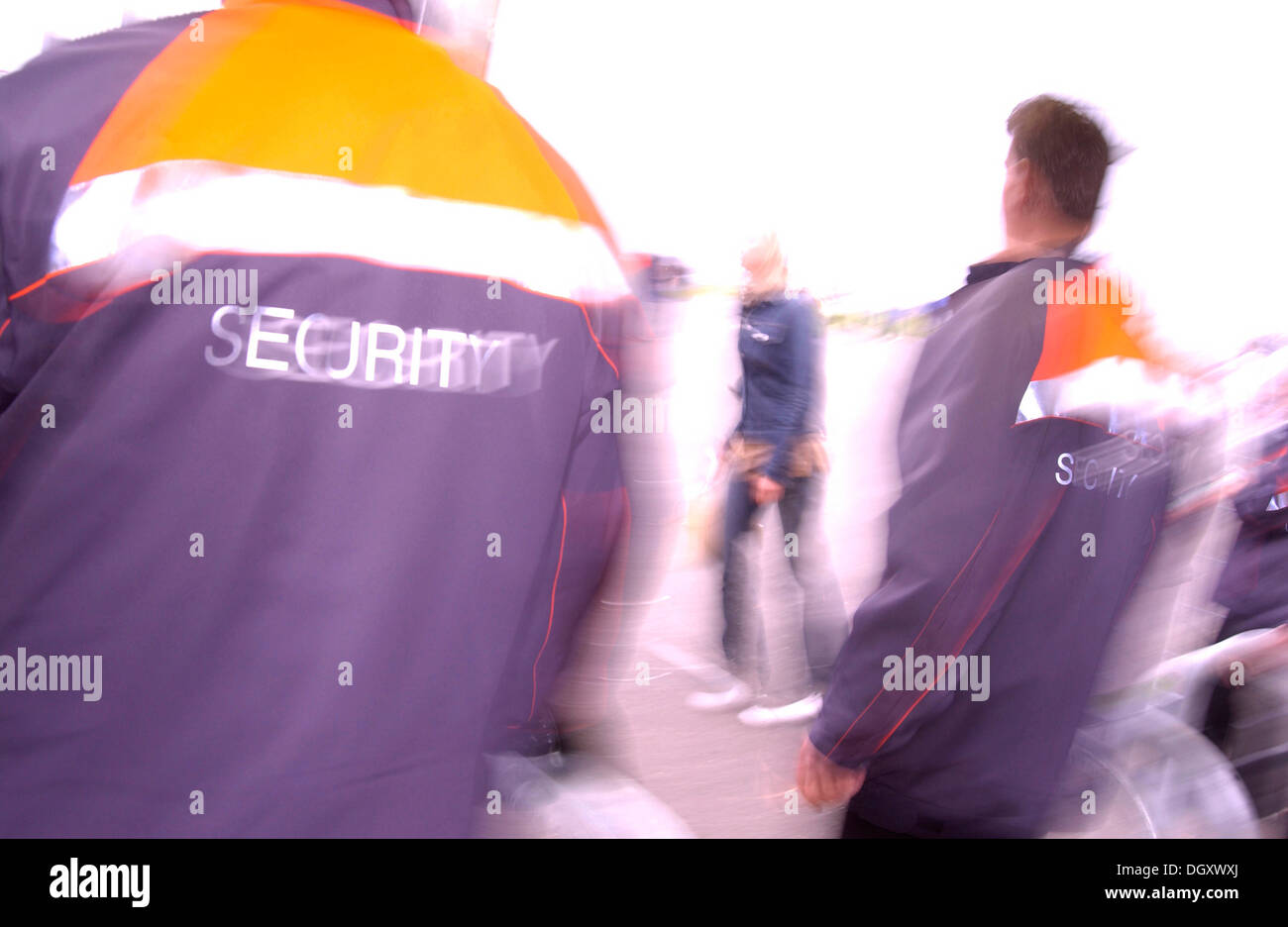 Men wearing security jackets, blurred from behind Stock Photo Alamy