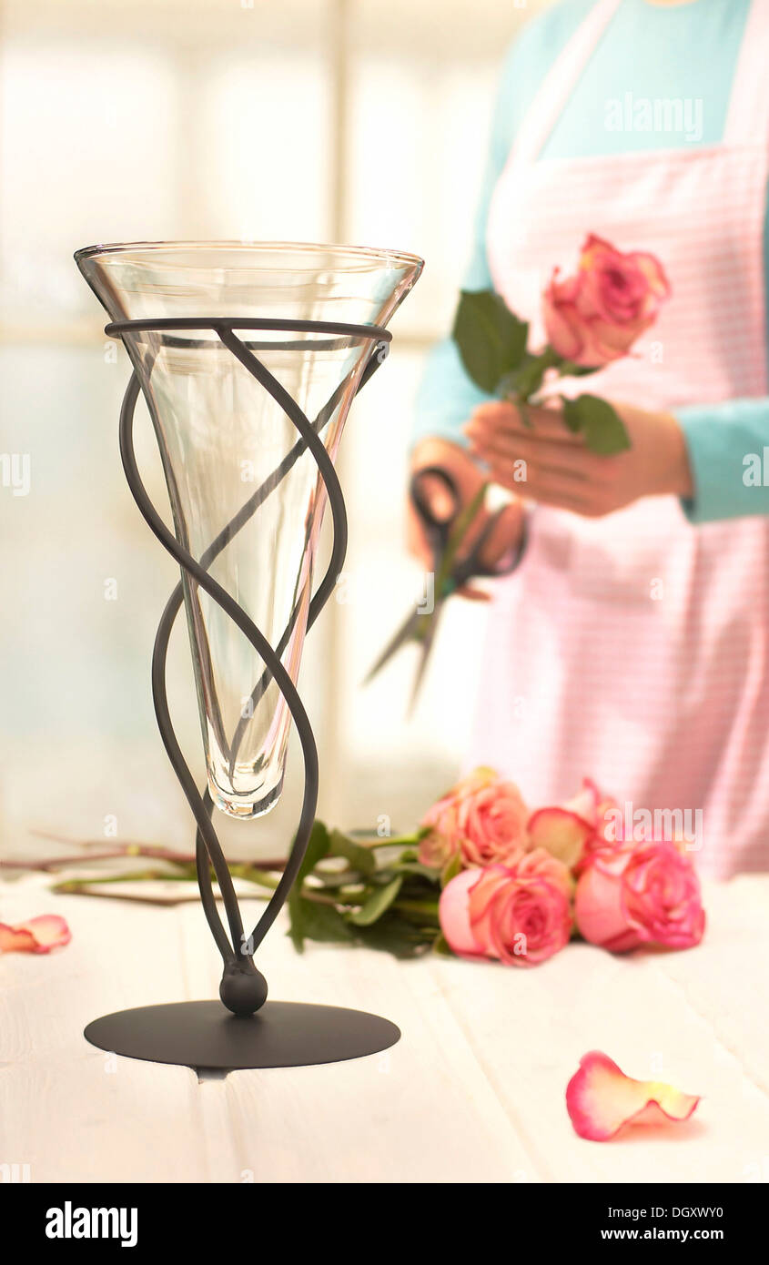Woman wearing an apron cutting roses for a vase of flowers Stock Photo