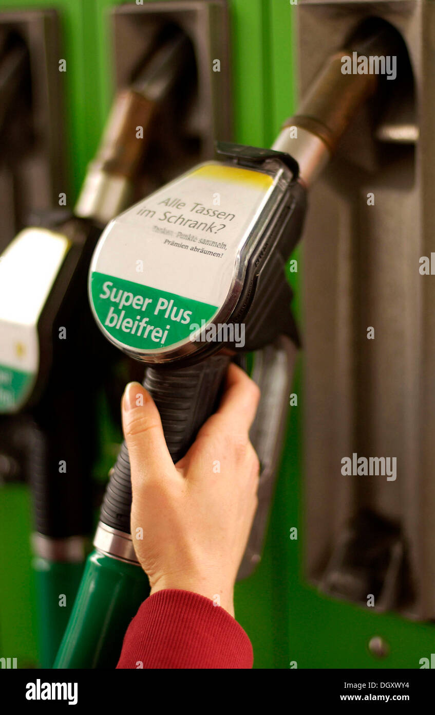 Woman's hand holding a fuel pump nozzle with Super Plus bleifrei, German for Super Plus Unleaded Stock Photo