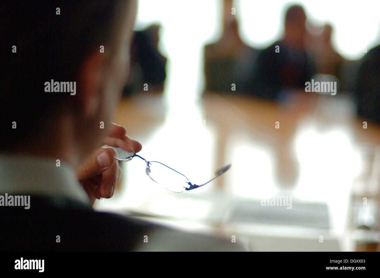 Meeting situation with the focus on glasses and hands, blurred people Stock Photo