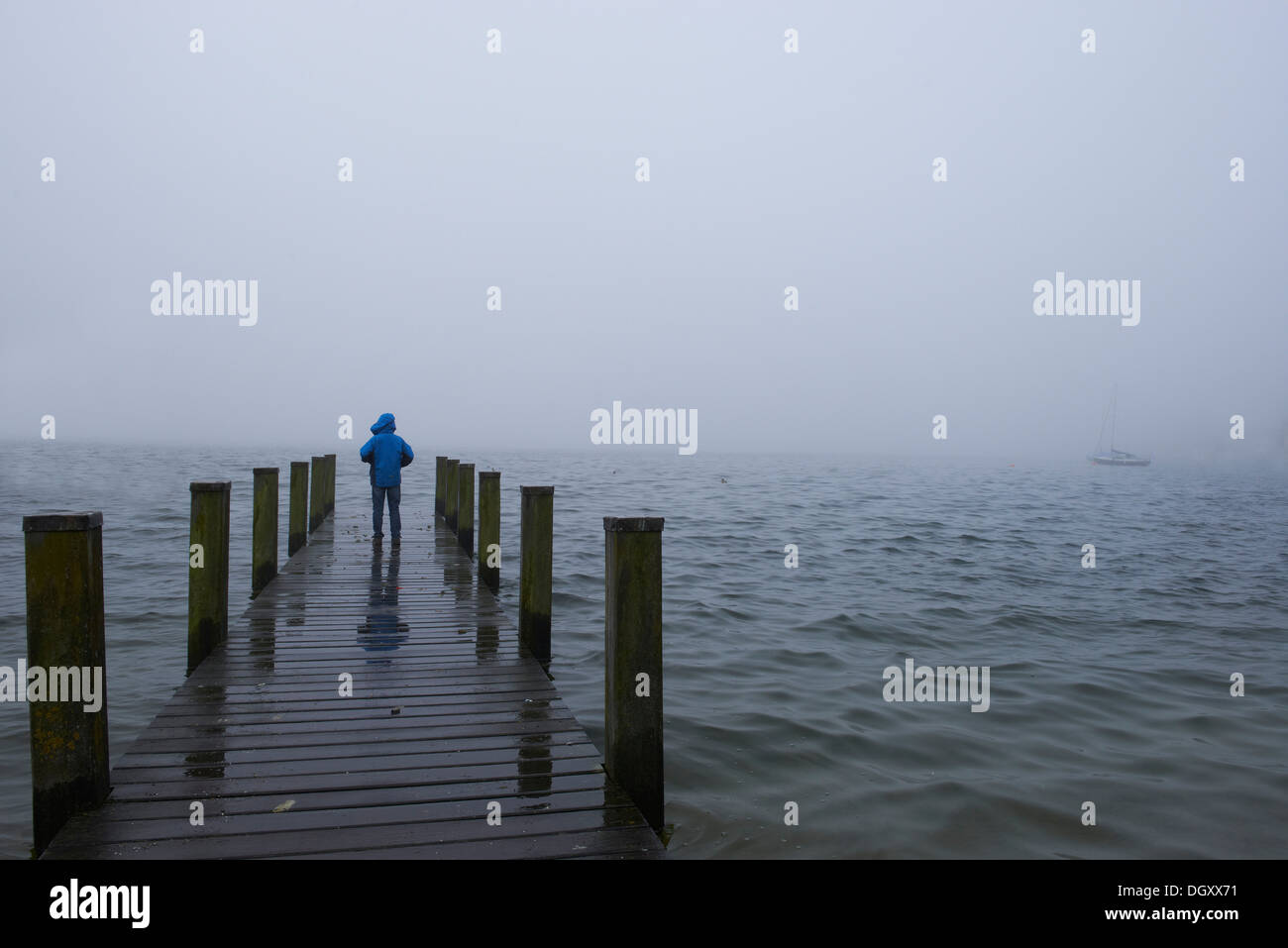Boy standing on a wooden jetty in the fog, Starnberger See, Starnberg, Upper Bavaria, Bavaria, Germany Stock Photo