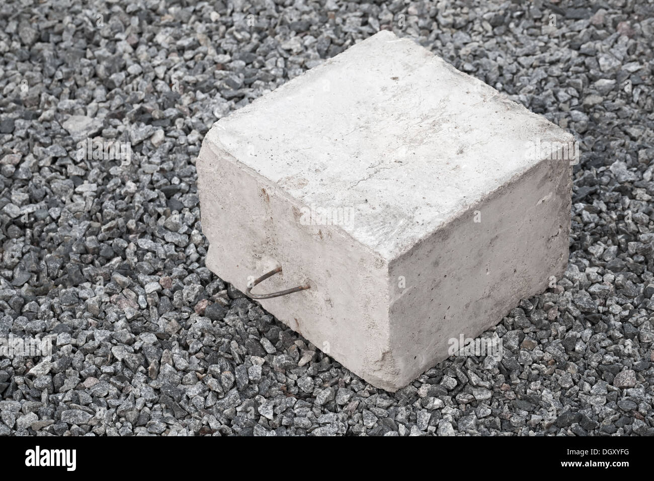 Big concrete construction block with metal lug on gray gravel Stock