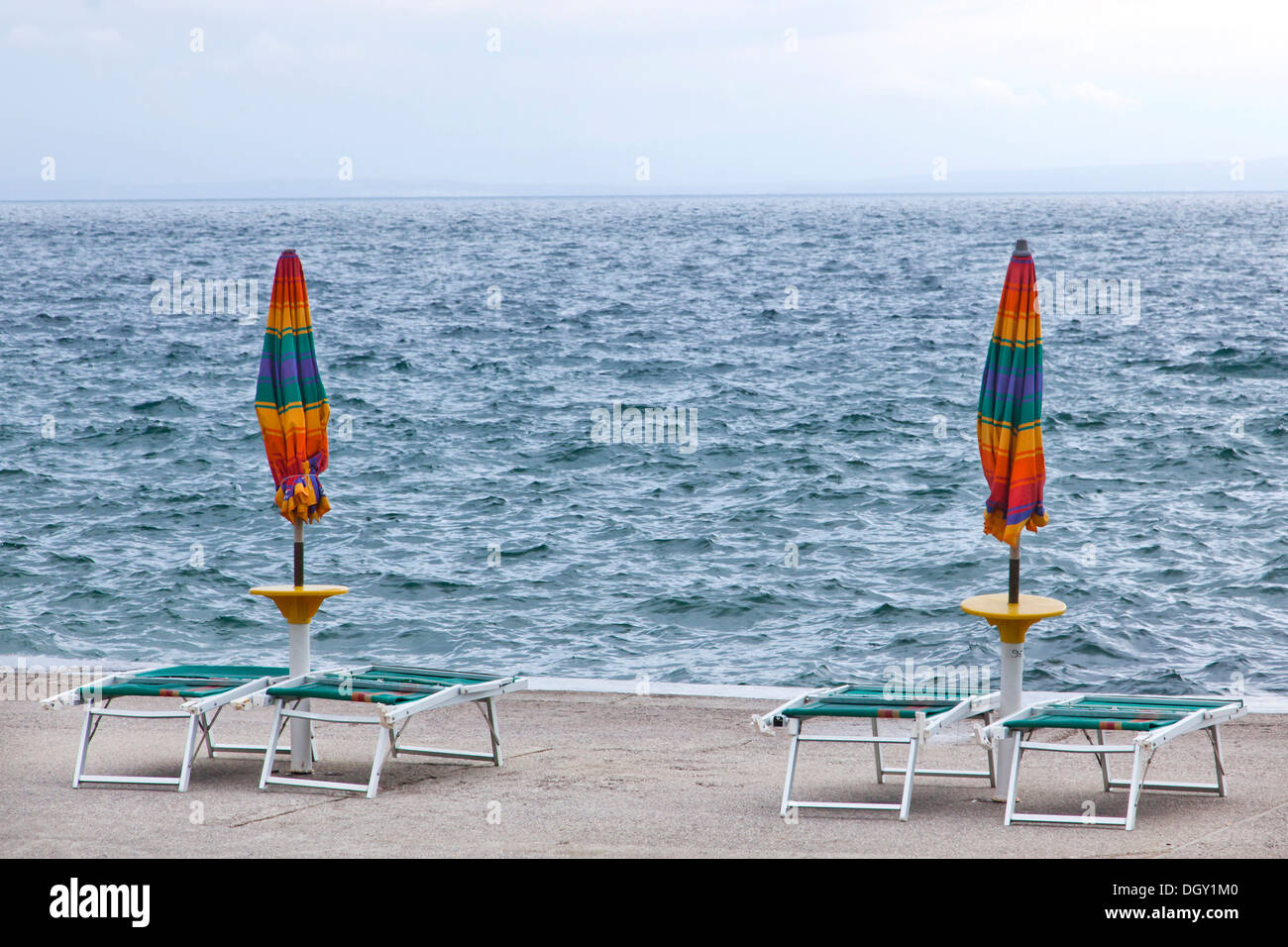 Umbrellas and deckchairs during the preseason on the beach of Opatija on the Mediterranean Sea in Kvarner Bay, Istria, Croatia Stock Photo