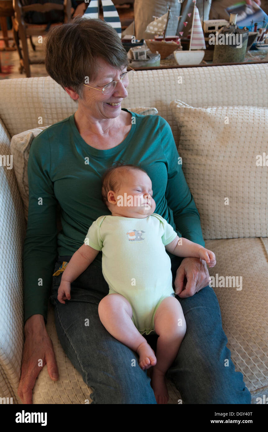 Little baby girl asleep lying on her grandmothers lap Stock Photo