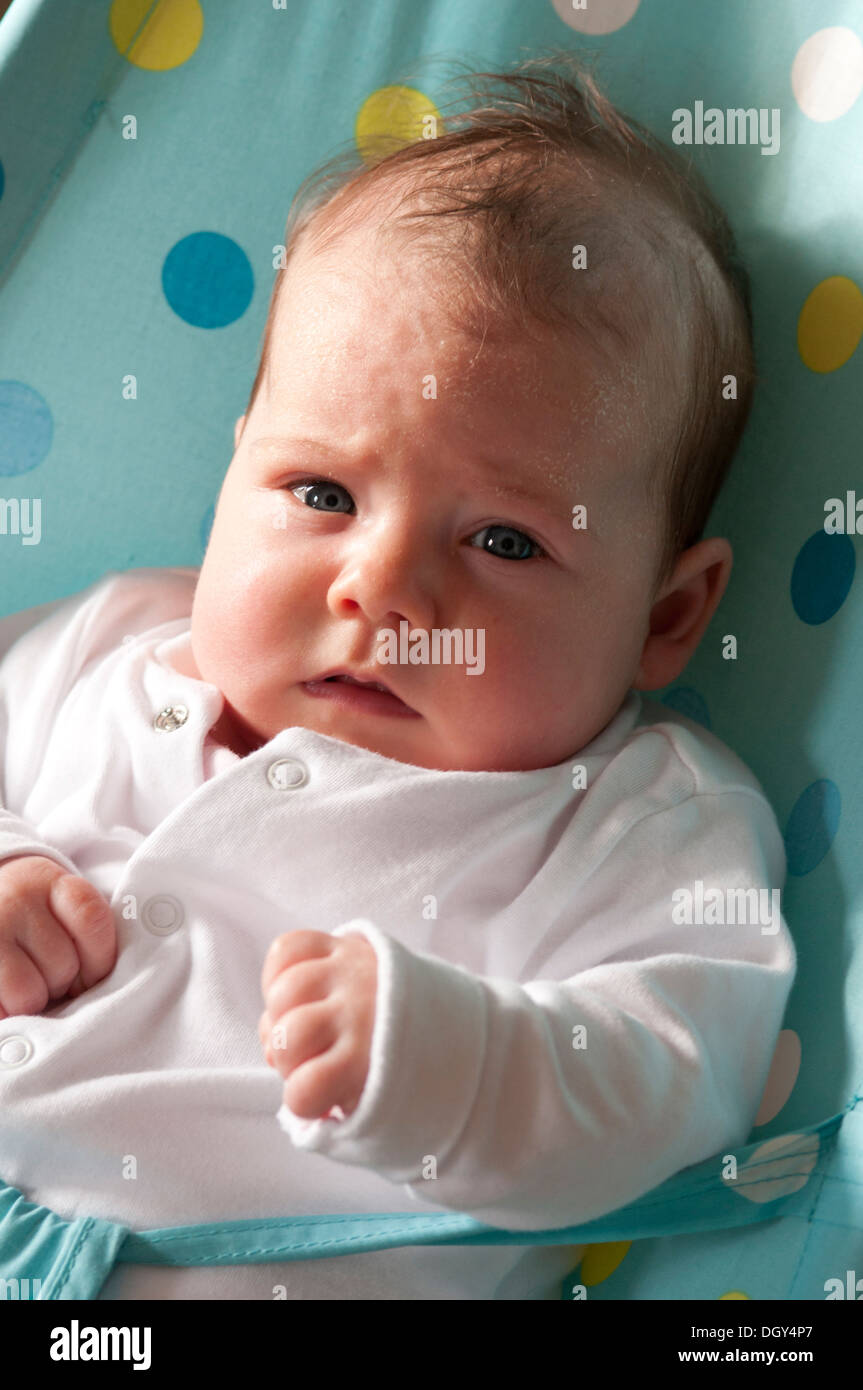 Portrait of little baby girl in a baby bouncer looking worried Stock Photo
