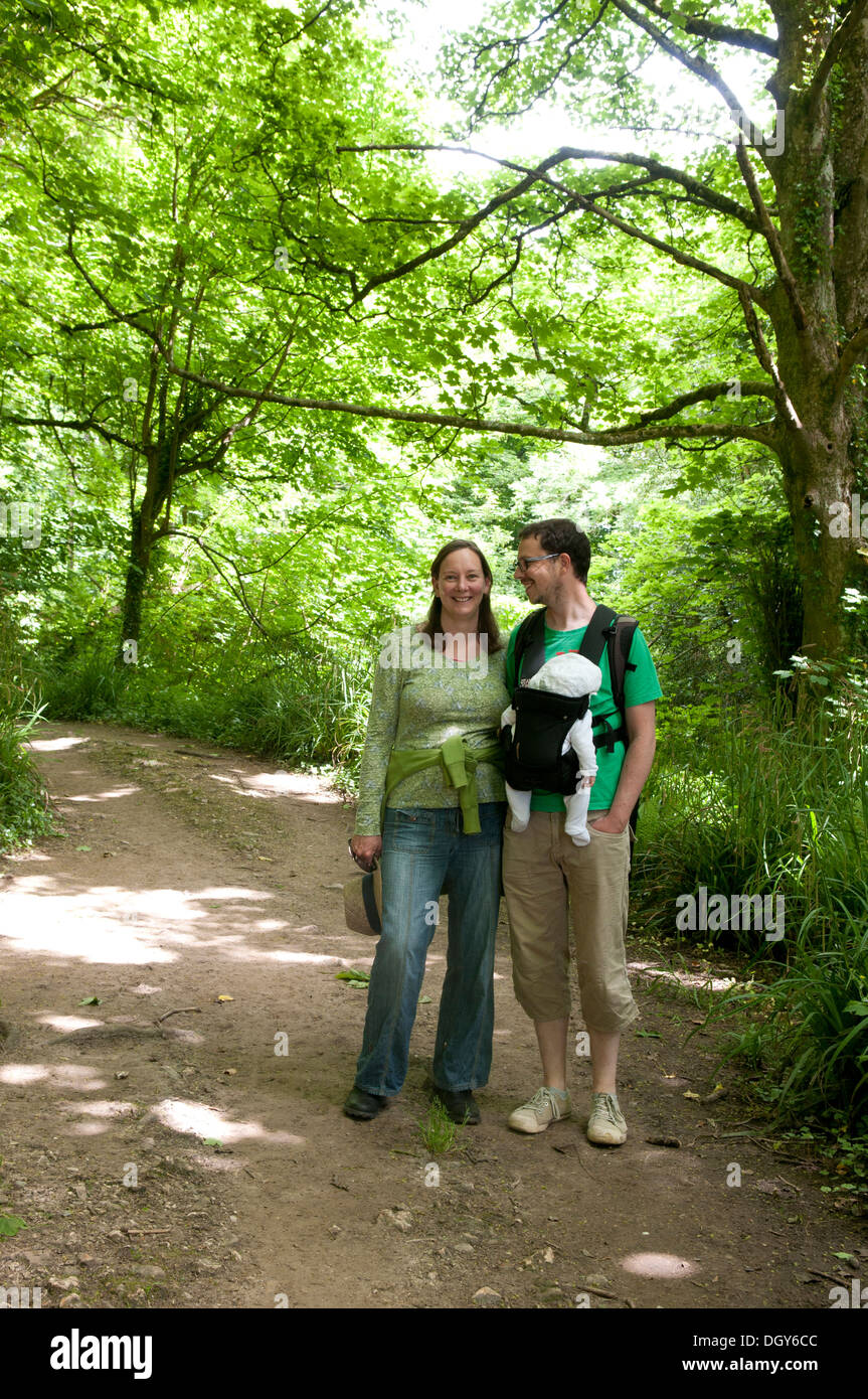 Couple with their little baby in a sling enjoying a walk in the countryside Stock Photo