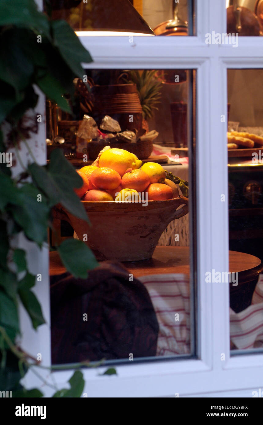 View from outside through a window into a kitchen decorated in a pre-Christmas style with a bowl of fruit and cakes Stock Photo