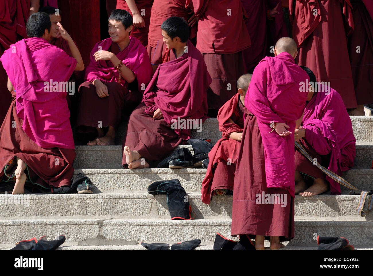 Tibetan monks in monk's robes on the steps in front of the assembly hall or Dukhang, Labrang Monastery, Xiahe, Gansu, China Stock Photo