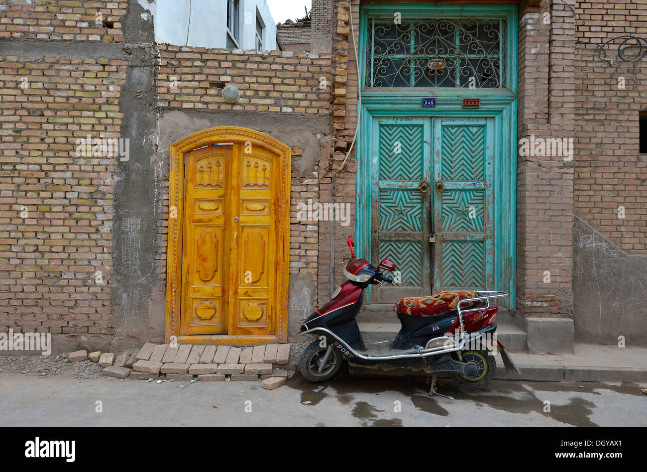 Motor scooter in front of old Uighur Muslim doorframes in new homes, Kashgar, Seidenstraße, Xinjiang, China Stock Photo