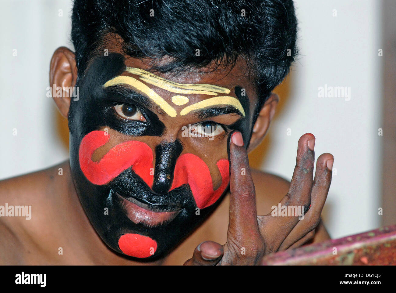 Applying the make-up for the power-hungry Kathakali character Chuvanna Thaadi, Kathakali dance theatre, Kochi, Kerala Stock Photo