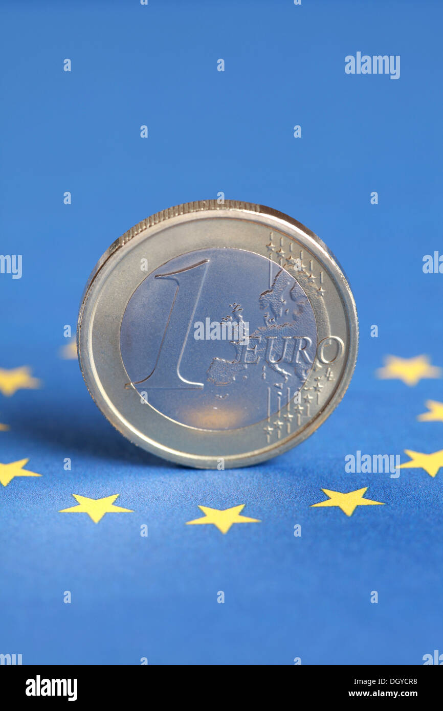 A one Euro coin stands on the flag of the EU Stock Photo