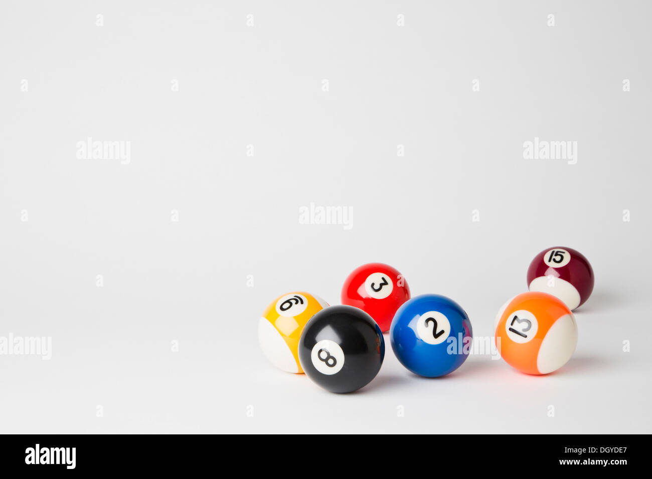 Six pool balls, including the eight ball, on a white surface Stock Photo