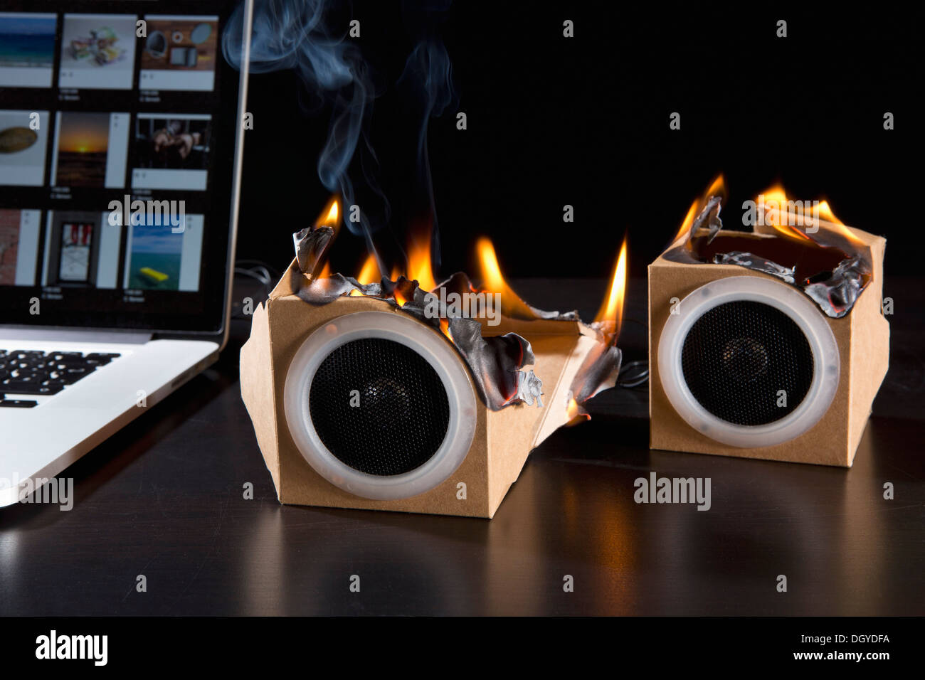 Two eco friendly cardboard audio speakers on fire next to a laptop
