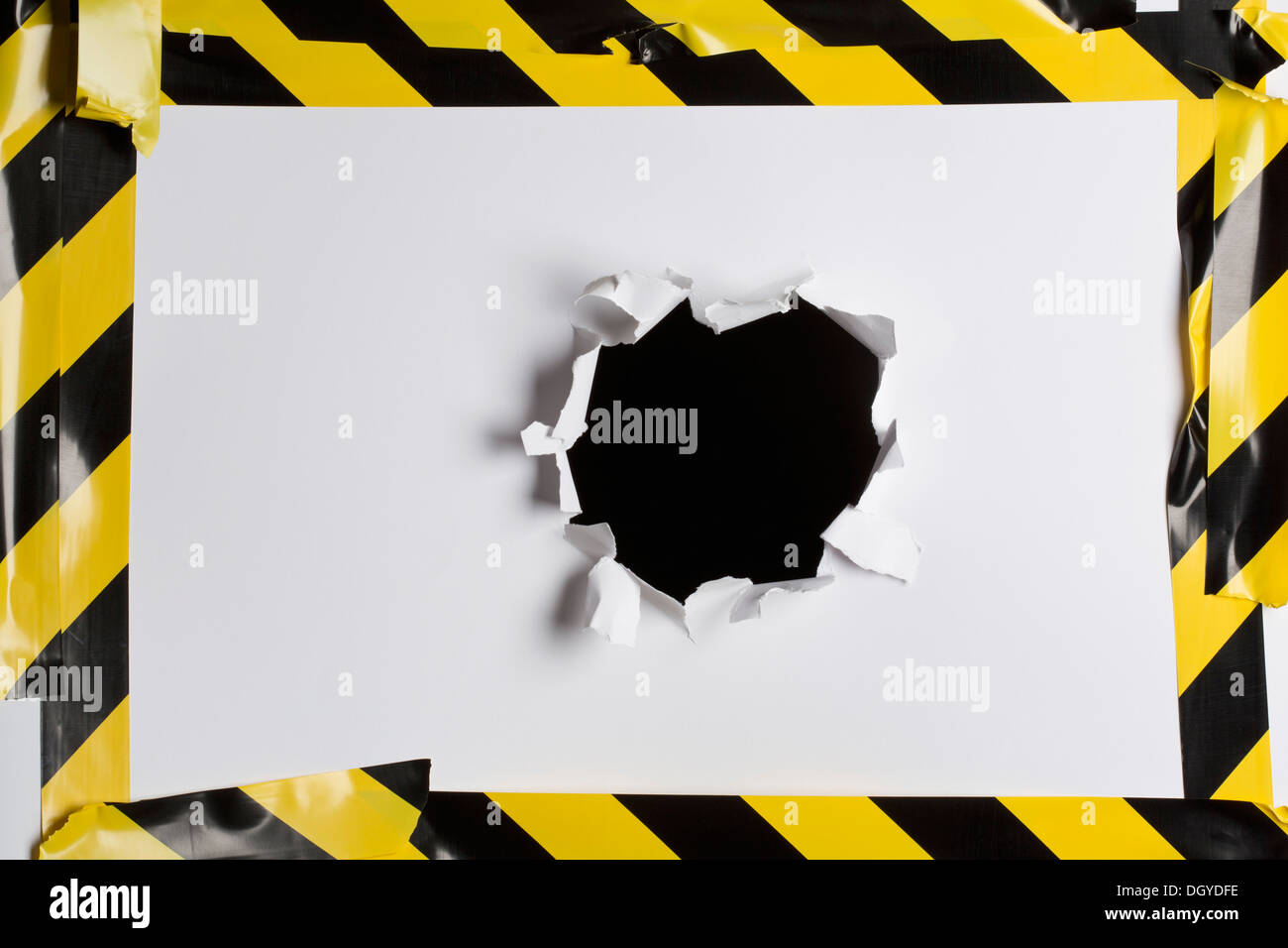 A punched out hole in cardboard with cordon tape around it Stock Photo