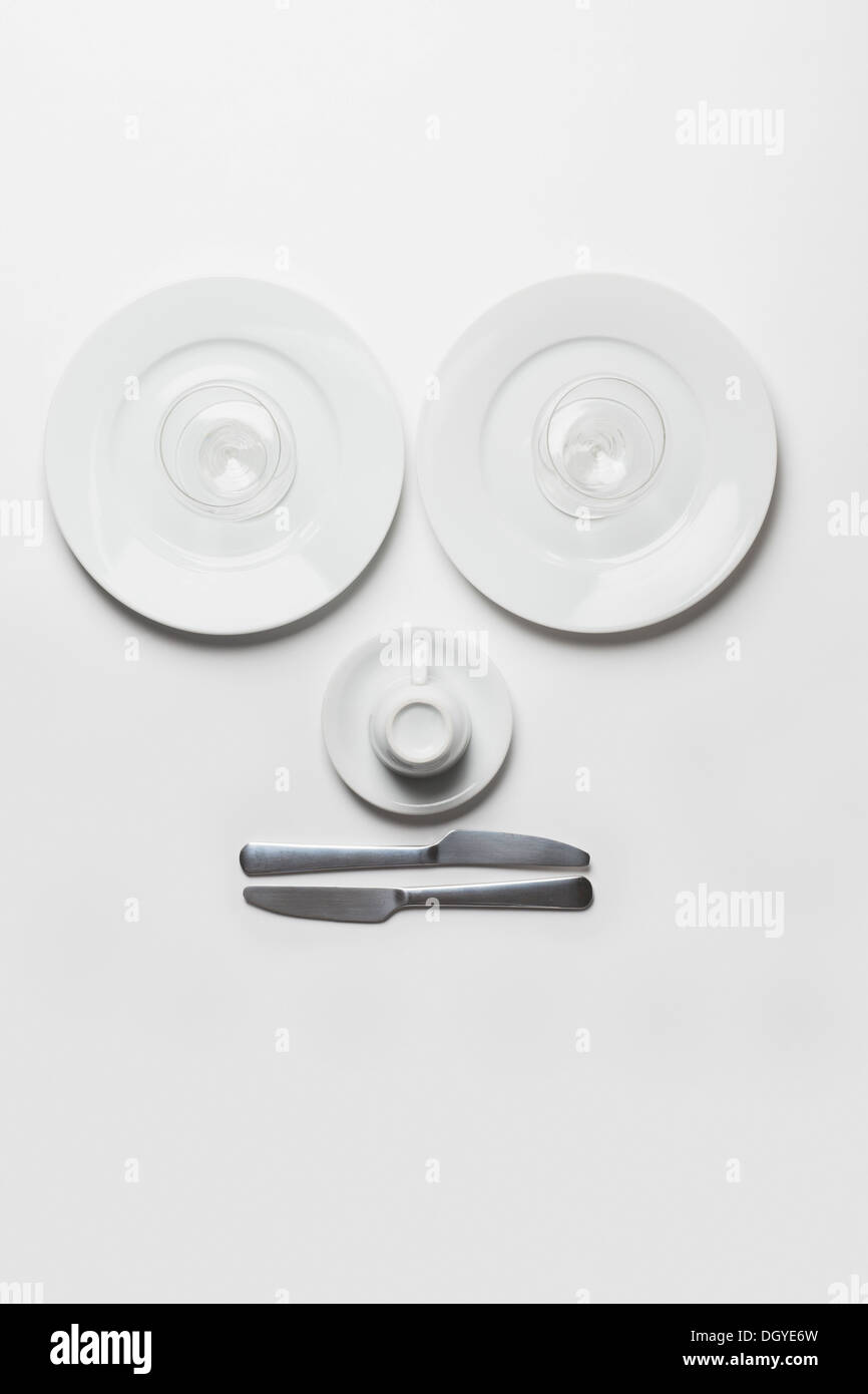 Anthropomorphic face made from plates, glasses, cup and knives Stock Photo