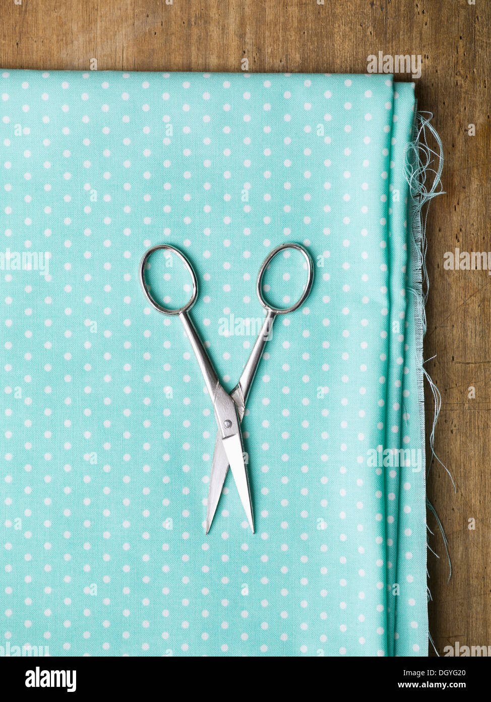 A pair of scissors on top of polka dotted fabric Stock Photo