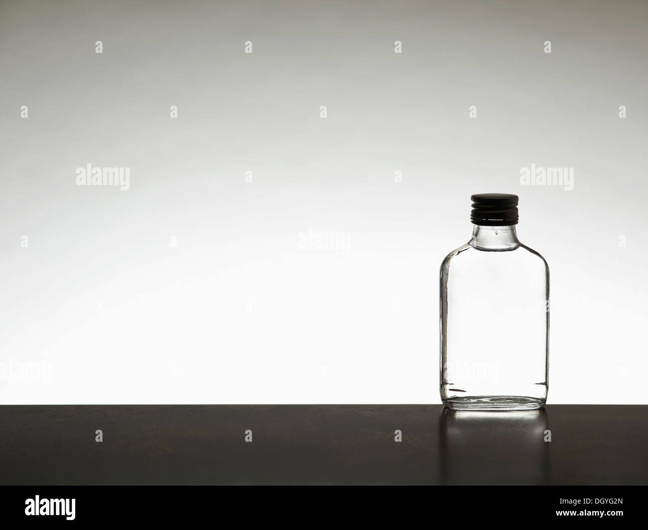 A miniature bottle of alcohol without a label, back lit Stock Photo
