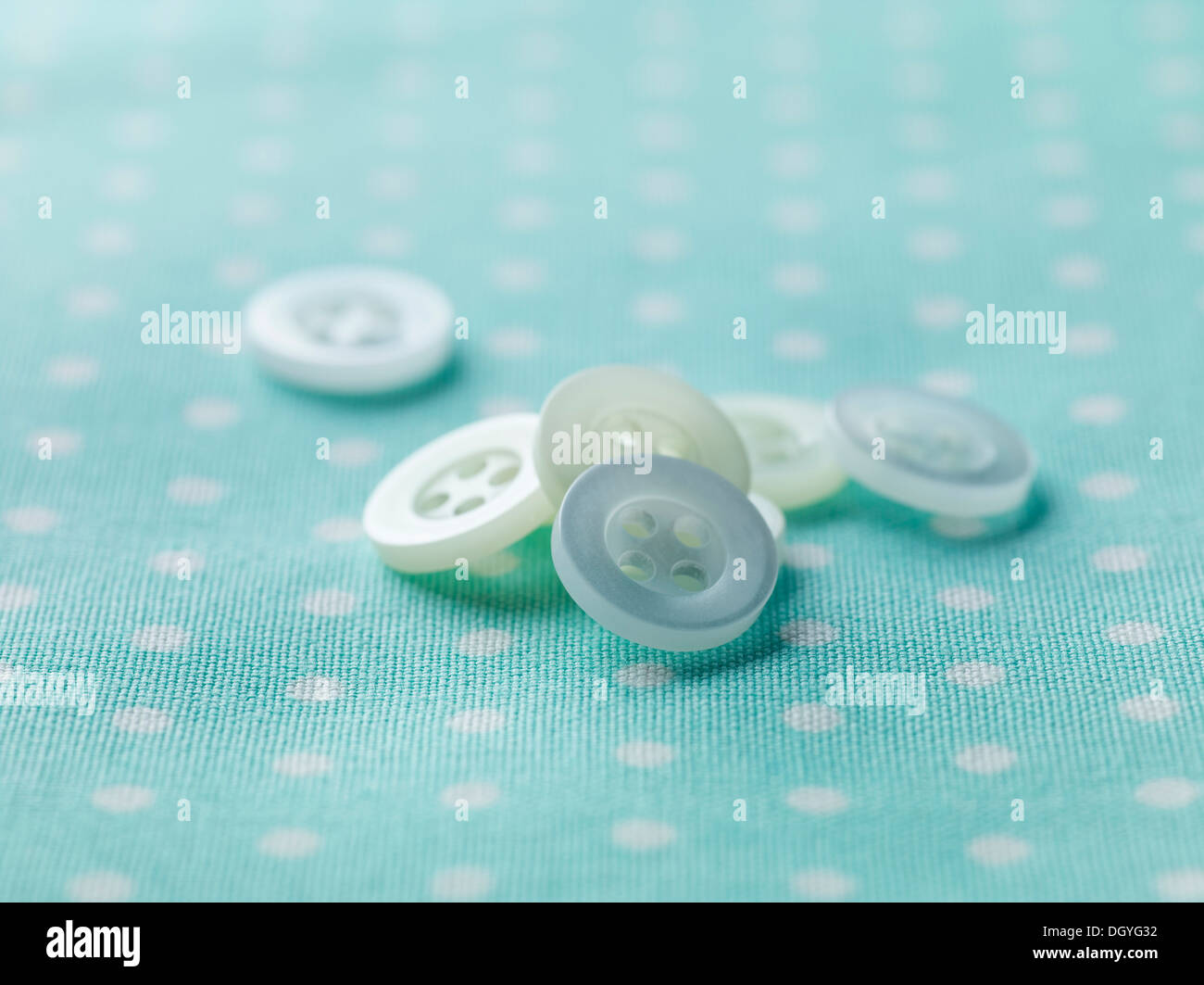 A pile of white buttons on patterned fabric Stock Photo