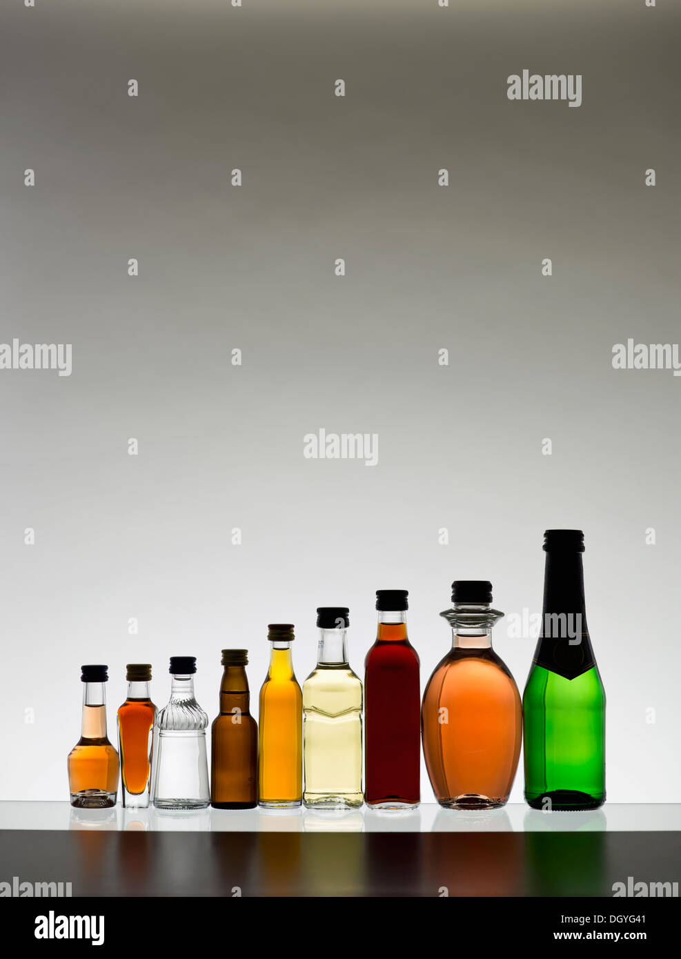 A line of various miniature bottles of alcohol without labels, back lit Stock Photo