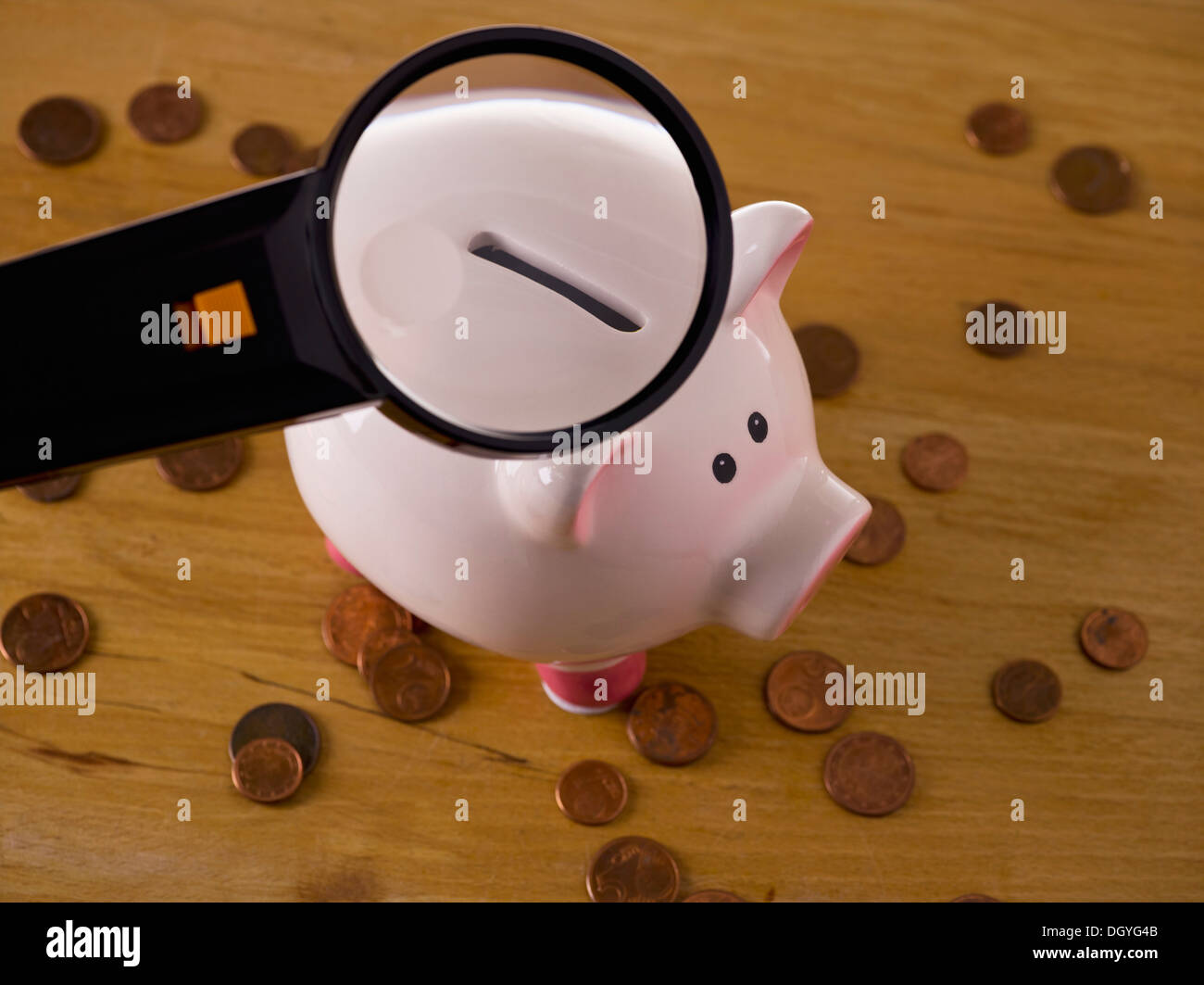 A magnifying glass magnifying slot on piggy bank hires stock