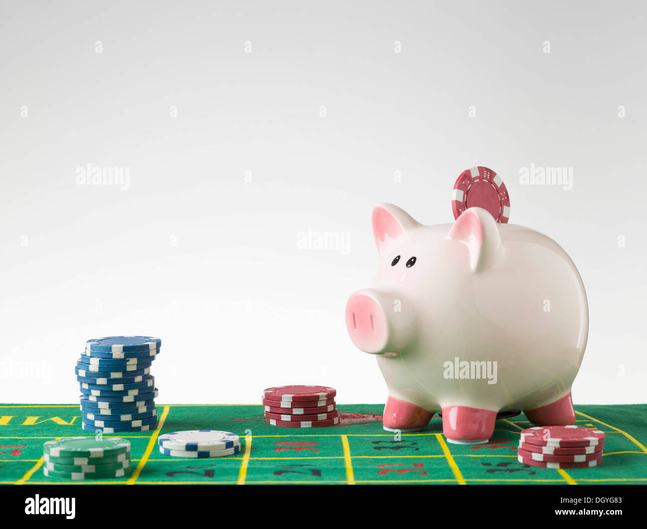 A piggy bank on a gambling table with stacks of gambling chips Stock Photo