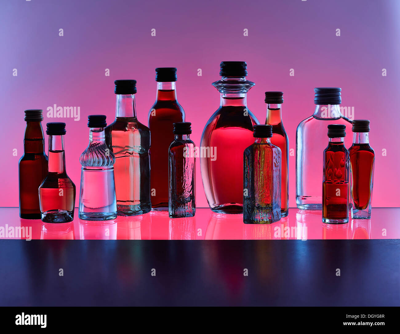 A grouping of various miniature bottles of alcohol without labels, back lit, colored background Stock Photo