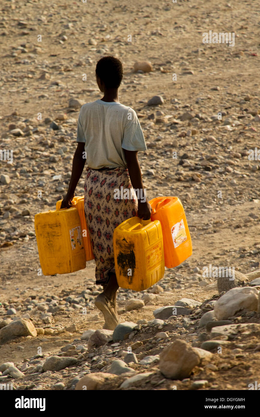 Afar woman carrying water jugs, Afar village of Hamed Ale, Danakil Depression, Ethiopia, Africa Stock Photo